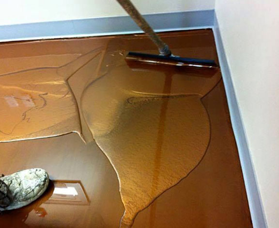 This image shows a man applying metallic epoxy to the floor.