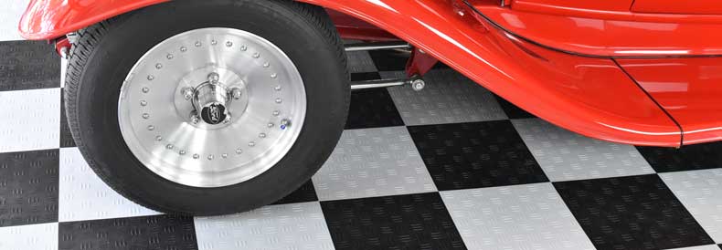This image shows a garage floor, A classic red car is parked there.